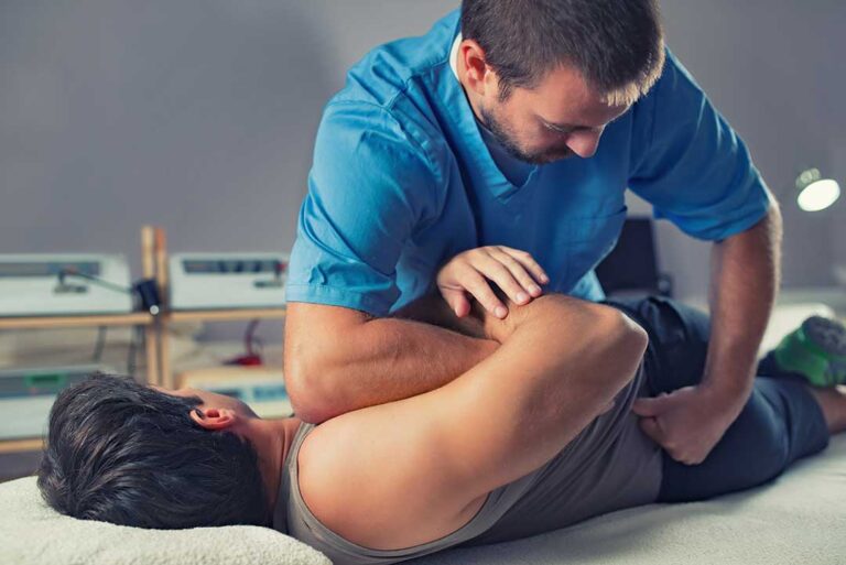 Clinician applying a controlled manual adjustment to a patient’s mid-back in a bright examination room.